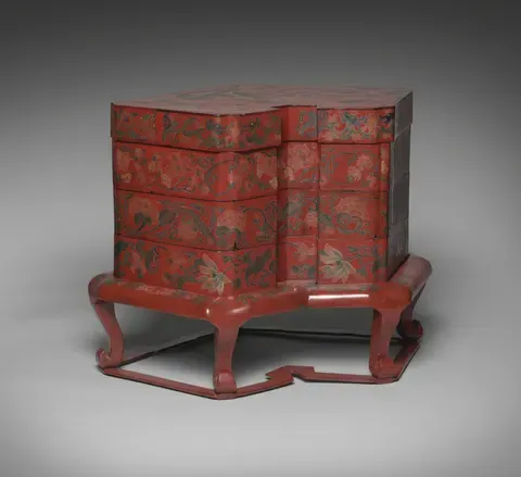 A tiered red lacquer box for kaiseki food, on its stand