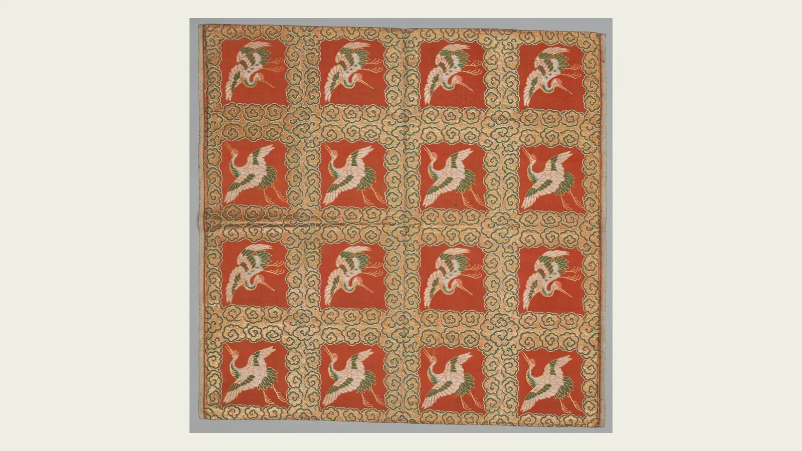 A brocaded fukusa, cranes woven in white on a grid of red squares over gold ground