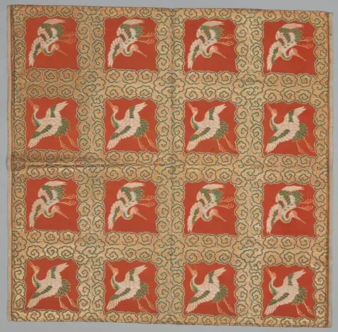 A brocaded fukusa, cranes woven in white on a grid of red squares over gold ground