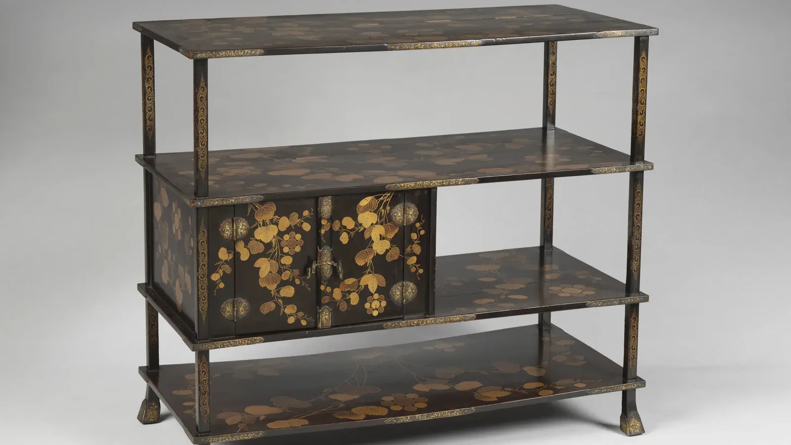 A black-and-gold tiered stand for displaying tea utensils