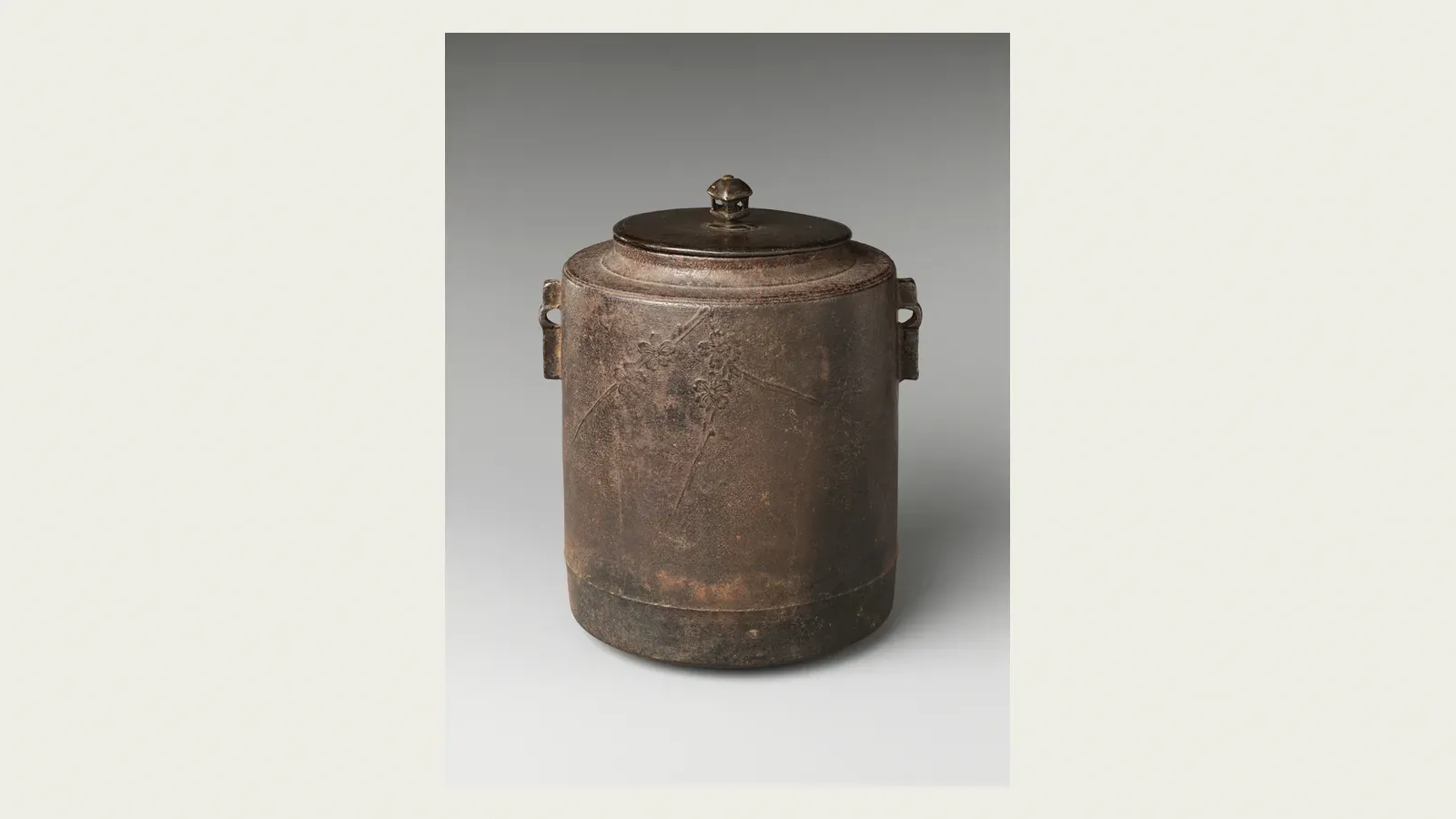 A cylindrical iron tea kettle with a bronze lid
