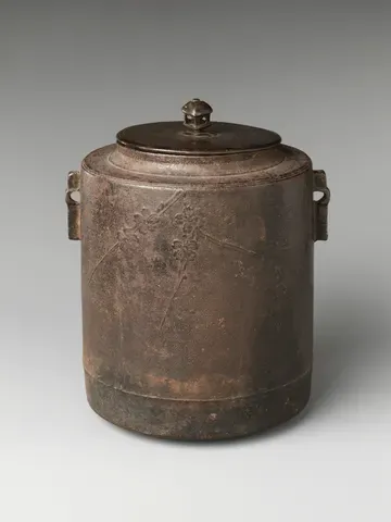 A cylindrical iron tea kettle with a bronze lid