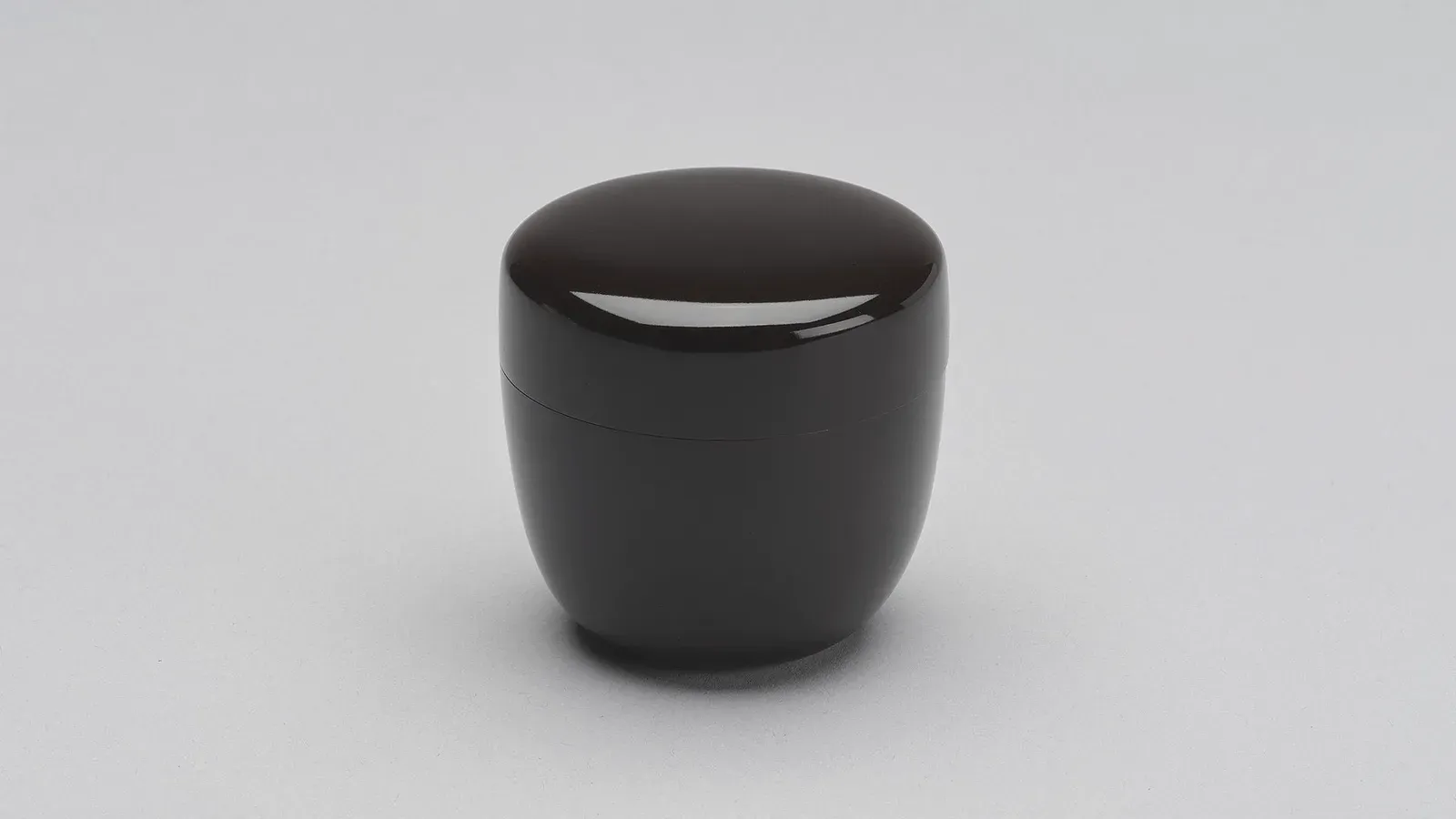 A plain black tea caddy, lid closed against the light