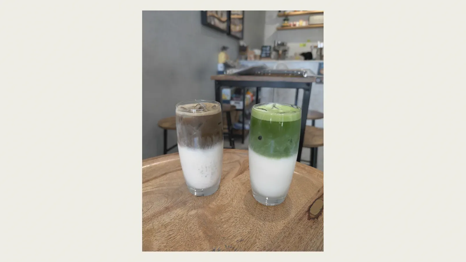 Two matcha lattes layered green over milk in tall glasses