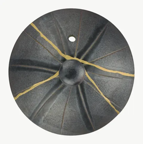 A dark bowl mended with gold, seams radiating across the glaze