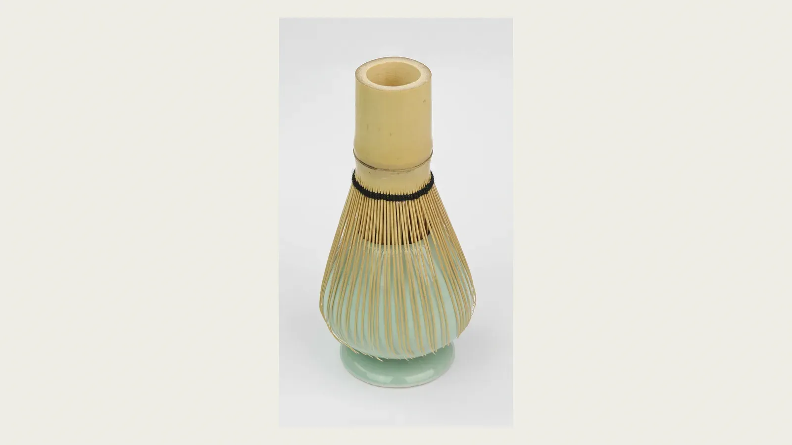 A bamboo whisk standing beside a small tea caddy